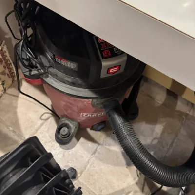 Craftsman 12-gallon 5.5 peak HP wet/dry shop vacuum stored under a shelf, showing minor cosmetic wear.