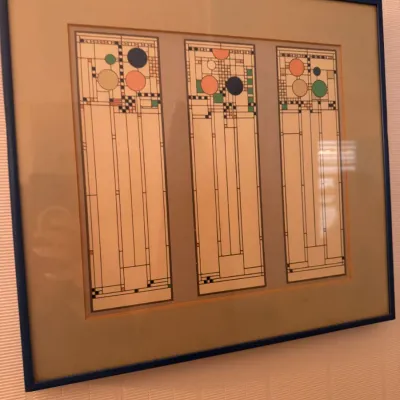 Framed triptych print depicting Frank Lloyd Wright Coonley Playhouse glass window designs in a thin blue frame.