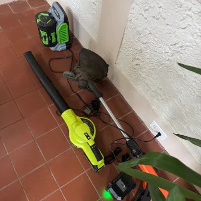 Collection of electric yard tools, including a Ryobi leaf blower, a Black & Decker string trimmer, an additional power tool battery,...