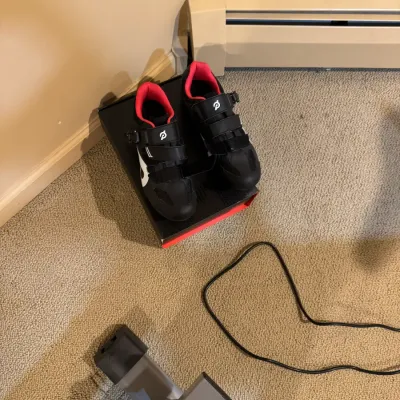 Pair of black and red Peloton cycling shoes sitting on top of their original shoe box.