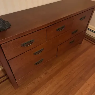 Dark reddish-brown wood dresser featuring six drawers with bronze-toned bail handle hardware.