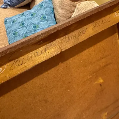 Handwritten signature and title inscription on the reverse of a wooden picture frame.