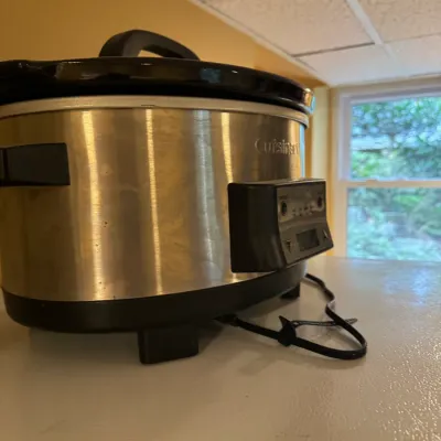 Cuisinart programmable slow cooker in brushed stainless steel finish with removable black ceramic pot and glass lid.
