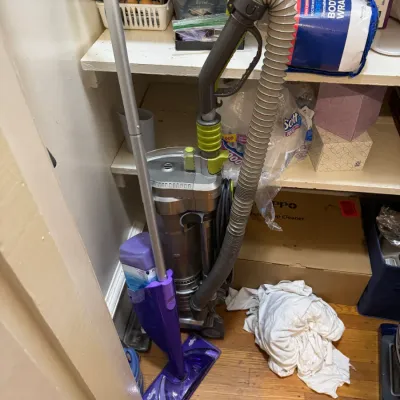 Dyson upright vacuum cleaner paired with a purple Swiffer WetJet floor mop, stored inside a closet.