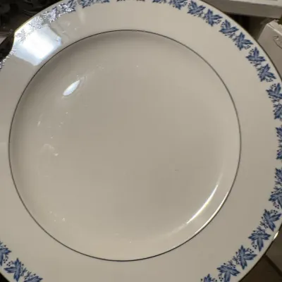 White porcelain dinner plate featuring a blue leaf motif rim with platinum trim.