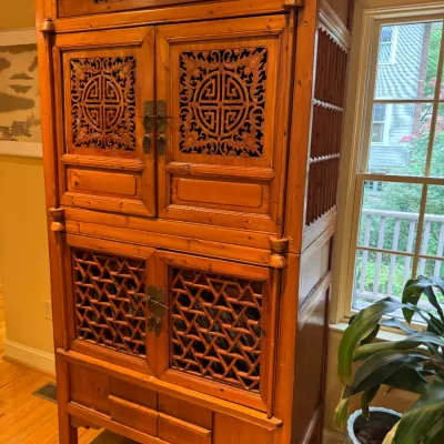 Traditional Chinese carved wood kitchen cabinet featuring intricate pierced lattice panels, round longevity symbol motifs, and original...