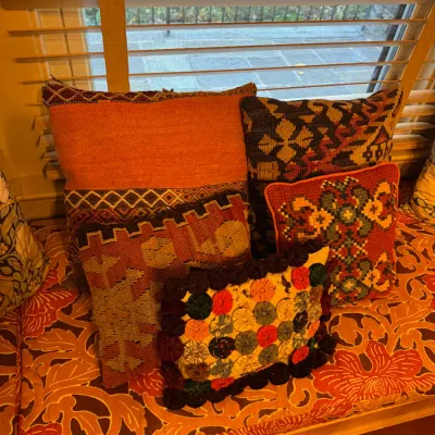 Collection of decorative throw pillows featuring kilim woven textiles, needlepoint patterns, and yo-yo quilt designs, arranged on a...
