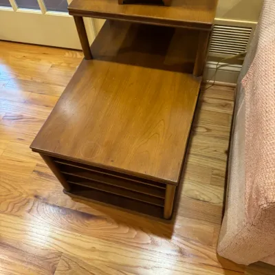 Mid-century modern two-tier wooden step end table with built-in lower slotted record or magazine storage, featuring surface wear and...