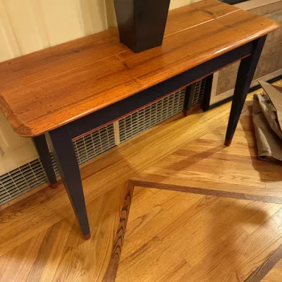 Country-style console table featuring a natural pine top, dark blue painted apron and tapered legs, with red accent striping and feet.