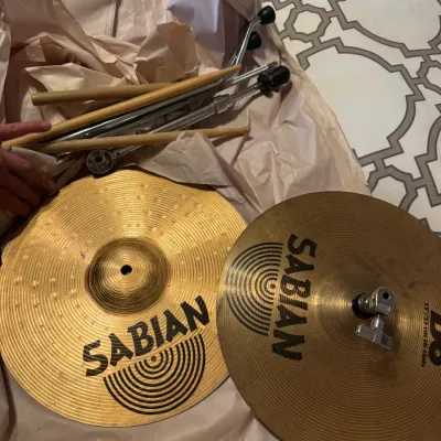 Pair of Sabian B8 13-inch hi-hat cymbals, complete with clutch, metal hardware stand pieces, and wooden drumsticks.
