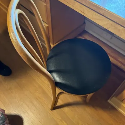 Vintage bentwood chair featuring a loop back frame and a round black cushioned vinyl seat.