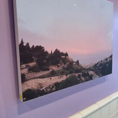 Canvas wall print featuring a scenic landscape photograph of a hillside town under a pink and purple sky.