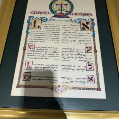 Framed illuminated artwork titled 'Creed for the Lawyer', featuring calligraphic biblical verses in English and Hebrew, housed...