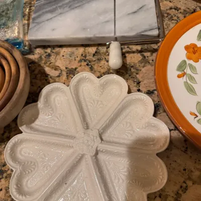 White ceramic flower-shaped divided serving dish paired with a gray-veined marble cheese slicer board.