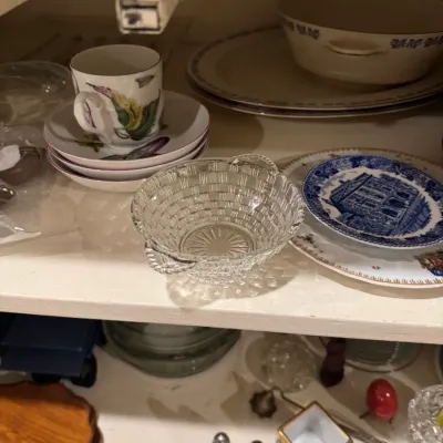 A collection of vintage tabletop items including a press glass basket bowl, blue-and-white transferware plates, floral teacups with...