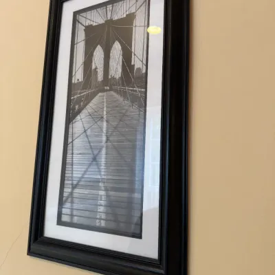 Framed black and white photograph of the Brooklyn Bridge, presented in a black wooden frame with white matting.