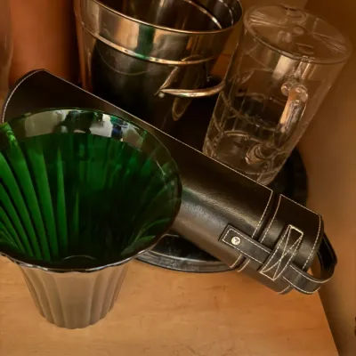 Assorted glassware, barware, and collectibles, including a green ribbed glass vase, a clear glass pitcher, a stainless steel bucket, and...