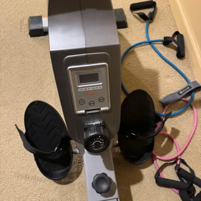 Sunny Health & Fitness magnetic rowing machine with digital monitor and adjustable tension dial, shown alongside exercise resistance...