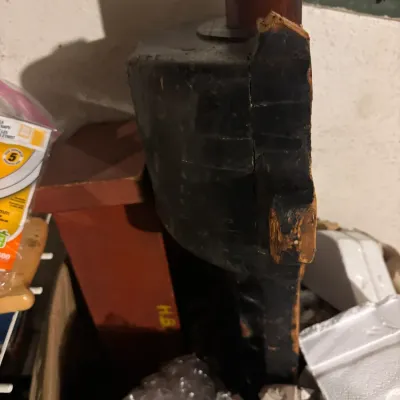 Vintage black and reddish-brown painted wooden object stored among packing materials and boxes.