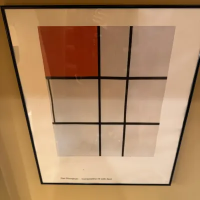 Framed exhibition art print of Piet Mondrian's Composition 8 with Red, presented in a slim black frame with white matting.