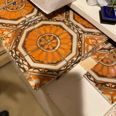 Vintage ceramic decorative tiles featuring an orange and brown floral medallion motif, likely from the 1970s.