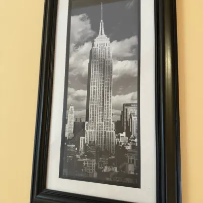 Framed black and white photograph of the Empire State Building in a dark wood frame with a white mat.