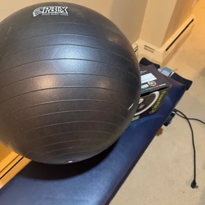 Black PBLX Pure Body Logix exercise stability ball resting on a blue workout bench.