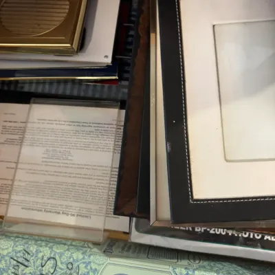 An assortment of desk accessories and framed items, including a leatherette picture frame, brass-tone compact, acrylic document holder,...