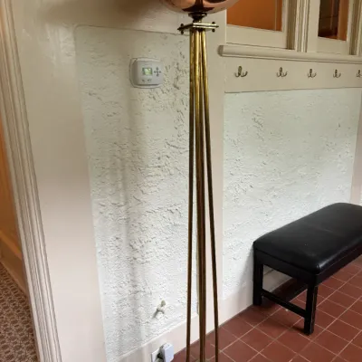 Mid-century Art Deco style torchiere floor lamp featuring brass tubular supports and a polished copper-toned bowl shade.