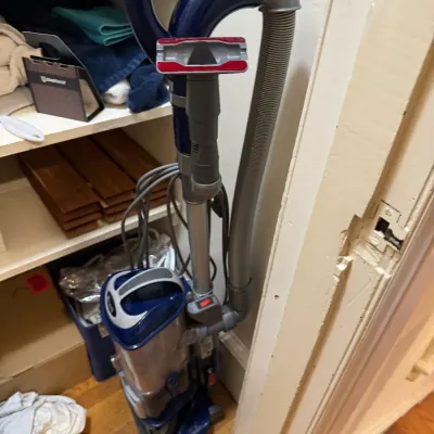 Shark Navigator upright bagless vacuum cleaner in navy blue and silver with attached hose and stair tool attachment.