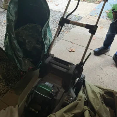 EGO Power+ cordless electric lawn mower with fold-down handle and attached grass catcher bag, shown in gently used condition.