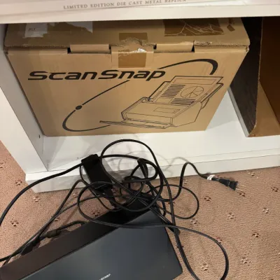Fujitsu ScanSnap desktop scanner with power cables and its original cardboard packaging box.