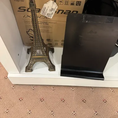 Bronze-tone metal miniature Eiffel Tower figurine alongside a black metal desk stand, placed in front of a boxed Fujitsu ScanSnap scanner.
