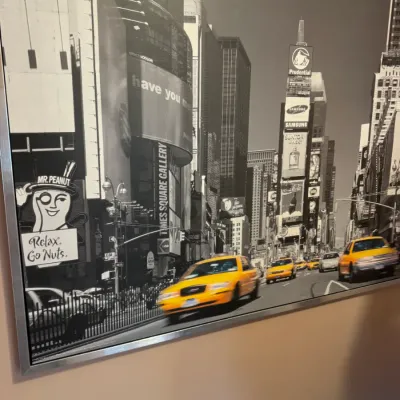 Large framed black-and-white canvas print of Times Square featuring selective yellow coloring on the iconic NYC taxis, housed in a thin...