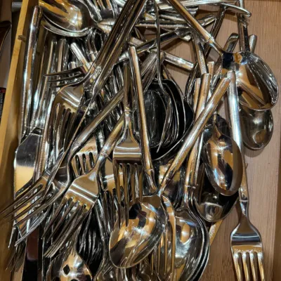 Large assortment of stainless steel flatware, including forks, spoons, and knives, packed in a wooden drawer organizer.