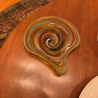 Hand-blown art glass dish or ashtray featuring a multicolor spiral swirl pattern within an amber body.