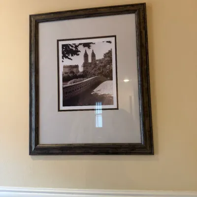 Framed black-and-white architectural photograph featuring Bow Bridge in Central Park, presented in a matted dark wood frame.