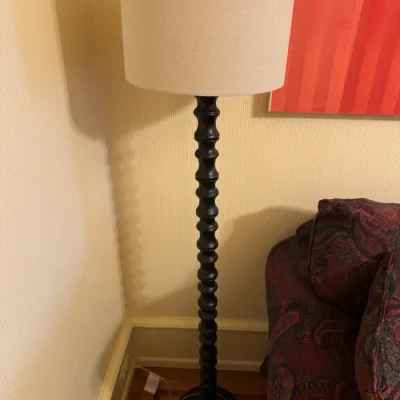 Contemporary dark wooden floor lamp featuring a stacked spindle pole and a beige fabric drum shade.