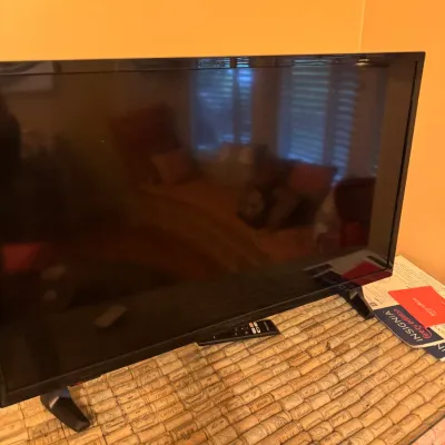 Insignia Fire TV Edition flat-screen television resting on a cork-topped table, includes remote control.