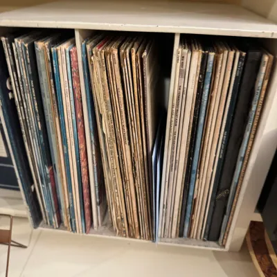 Collection of vintage 33 RPM vinyl records housed in a white wooden storage rack, including rock, pop, and soundtrack albums.
