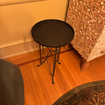 Black metal tray-top side table featuring cross-braced tripod legs with claw feet.