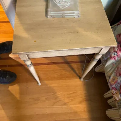 Off-white square end table with tapered legs, topped with a modern clear acrylic lamp base.