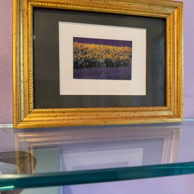 Framed photographic print depicting a field of sunflowers at dusk, presented in a double mat with a distressed gilt-finish ornate wooden...