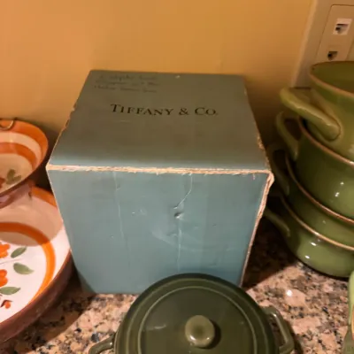Vintage Tiffany & Co. robin's egg blue gift box surrounded by green ceramic cookware and floral kitchenware.