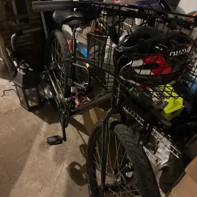 Black commuter bicycle equipped with a front wire cargo basket holding a Giro brand cycling helmet.