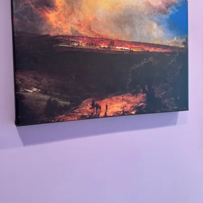 Wrapped canvas print depicting a dramatic landscape scene under a stormy sky, mounted on a purple wall.