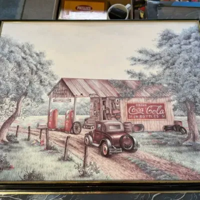 Sale Photo Thumbnail #239: Framed nostalgia art print depicting a vintage rural gas station and vintage automobile, framed in a simple black and gold-tone frame.