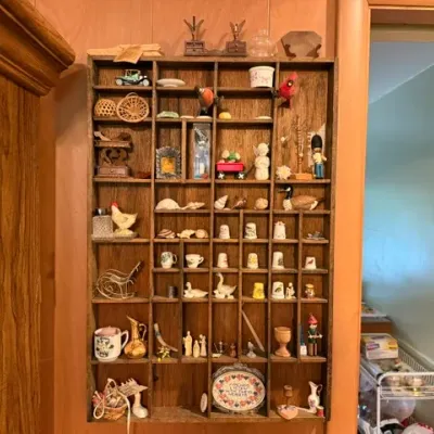 Sale Photo Thumbnail #71: Vintage wall-mounted wooden shadow box display shelf filled with various knick-knacks, figurines, thimbles, and miniatures.