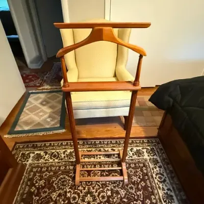 Sale Photo Thumbnail #163: Vintage mid-century wooden valet stand featuring an integrated jacket hanger, accessory tray, trousers bar, and shoe rack base.