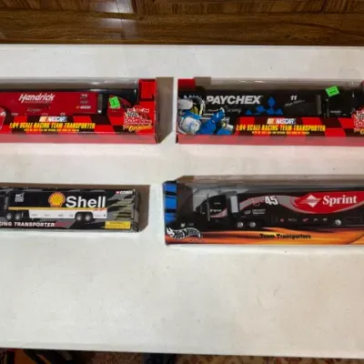 Sale Photo Thumbnail #75: Collection of four 1:64 scale die-cast racing team transporters in original packaging, including Racing Champions Hendrick Motorsports and Paychex models, a Corgi Shell rig, and a Hot Wheels Sprint rig.